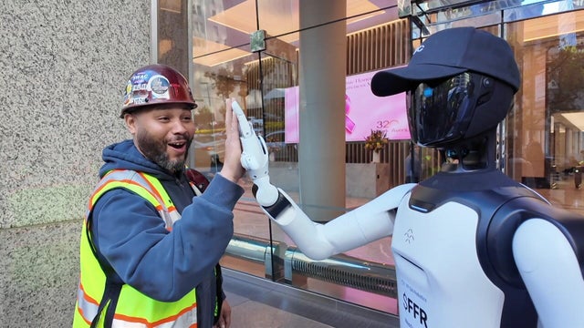 A man high-fives the Futurist humanoid robot 