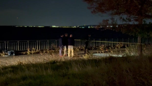 NYPD investigators looking at a bike path at night 